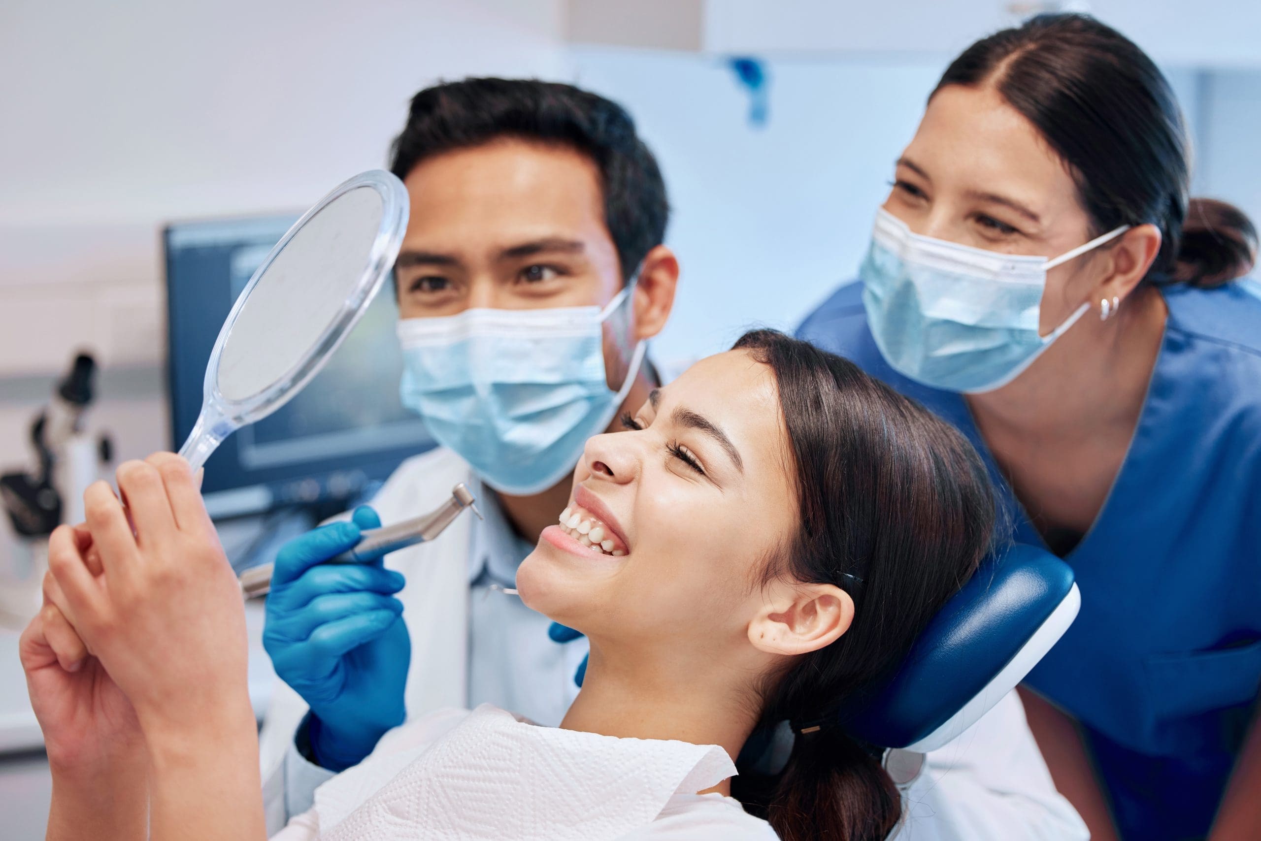 She's excited about her new smile. a young woman checking her results in the dentists office.